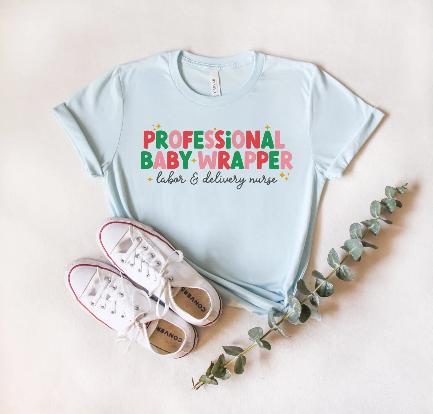 light blue "professional baby wrapper" t-shirt with christmas colored text
