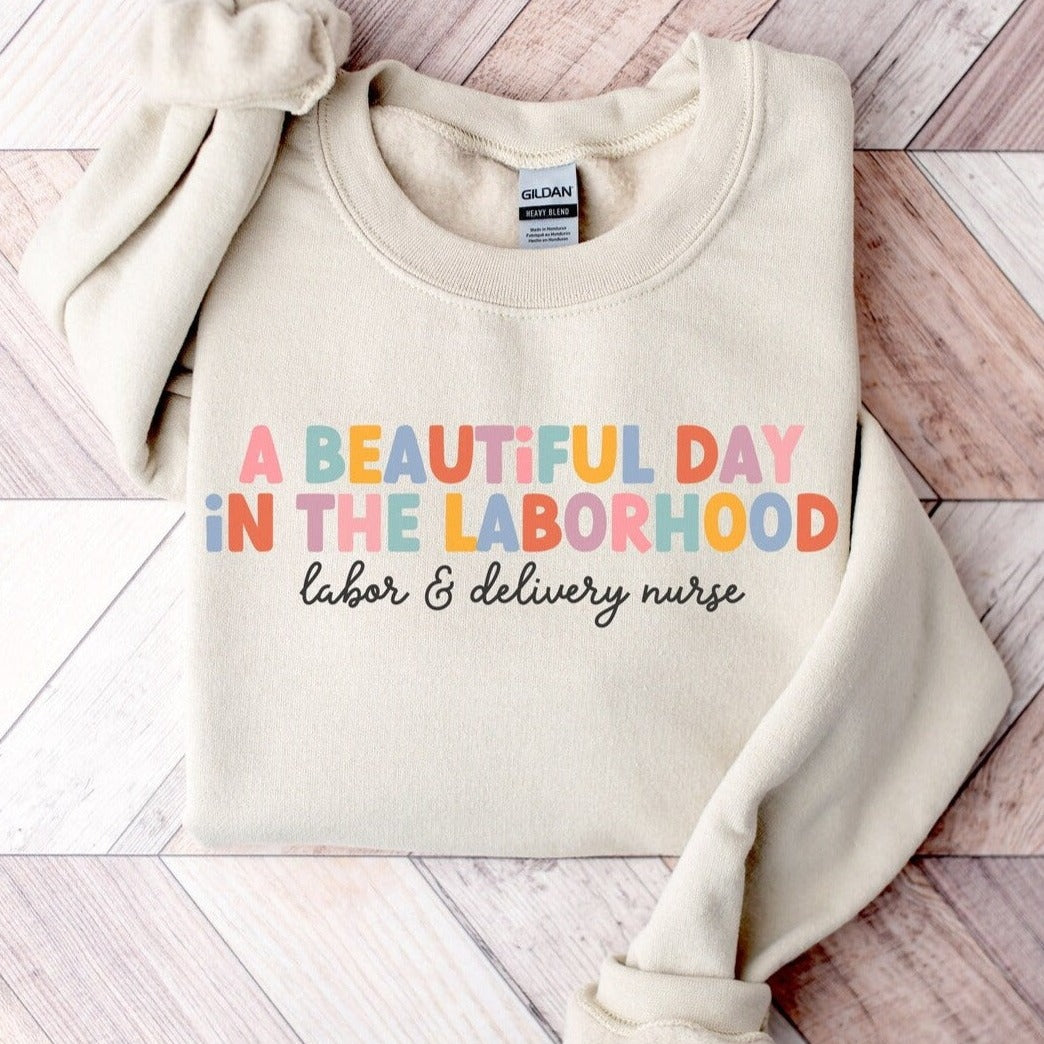 tan "a beautiful day in the laborhood" labor and delivery nurse sweatshirt