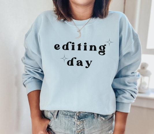 light blue "editing day" sweatshirt with retro text